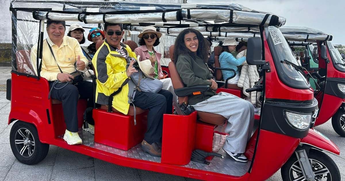 Happy travellers aboard a red 100% electric tuk-tuk in Porto