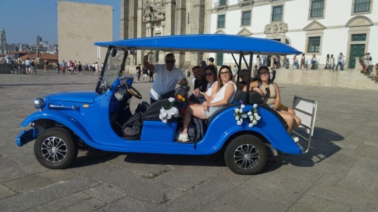 Travellers in a blue vintage-style electric tour vehicle beside Porto Cathedral