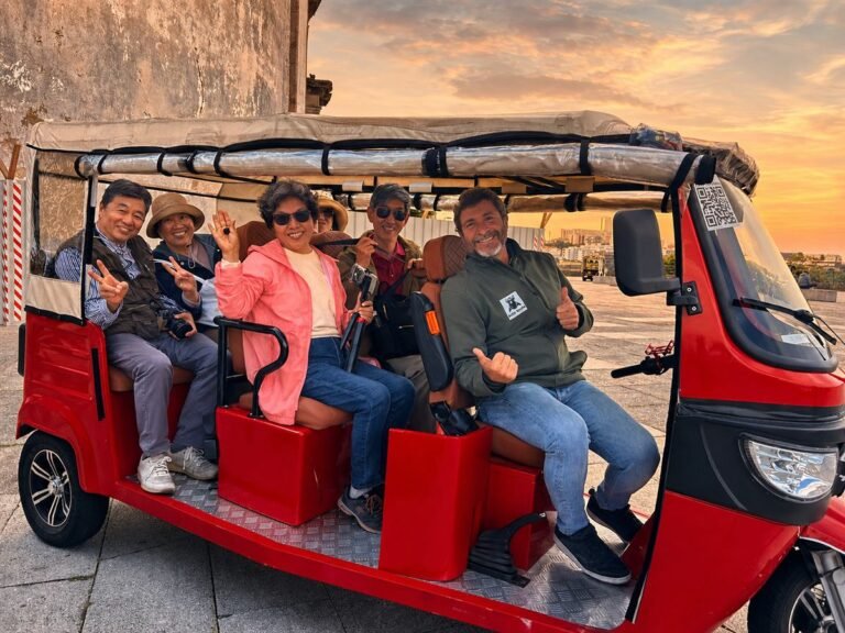Smiling guests and their guide in a private red tuk-tuk at sunset in Porto